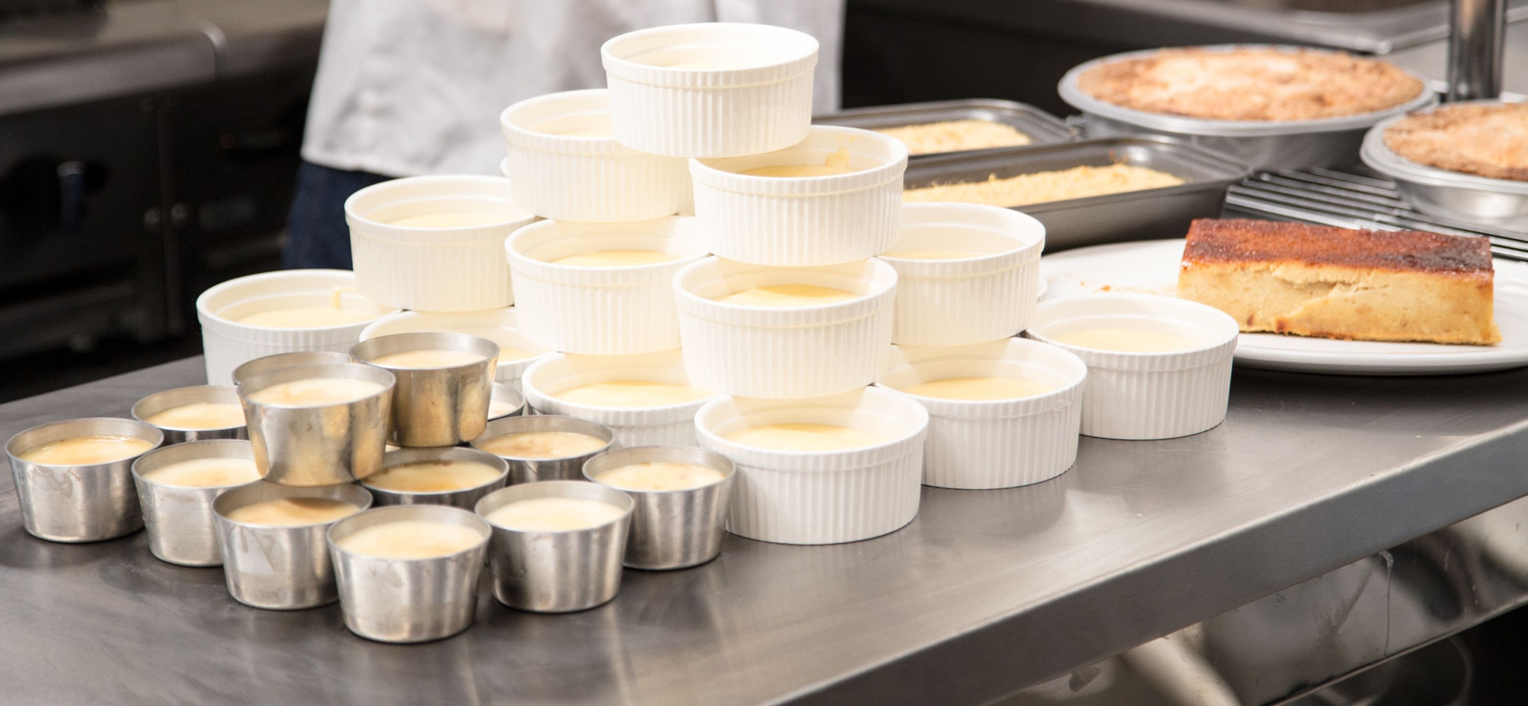 A kitchen with multiple ramekins and baking trays, likely for preparing desserts.