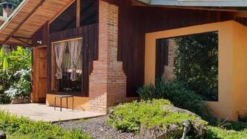 Una casa moderna con chimenea de ladrillo, ventanas amplias y una terraza de madera.