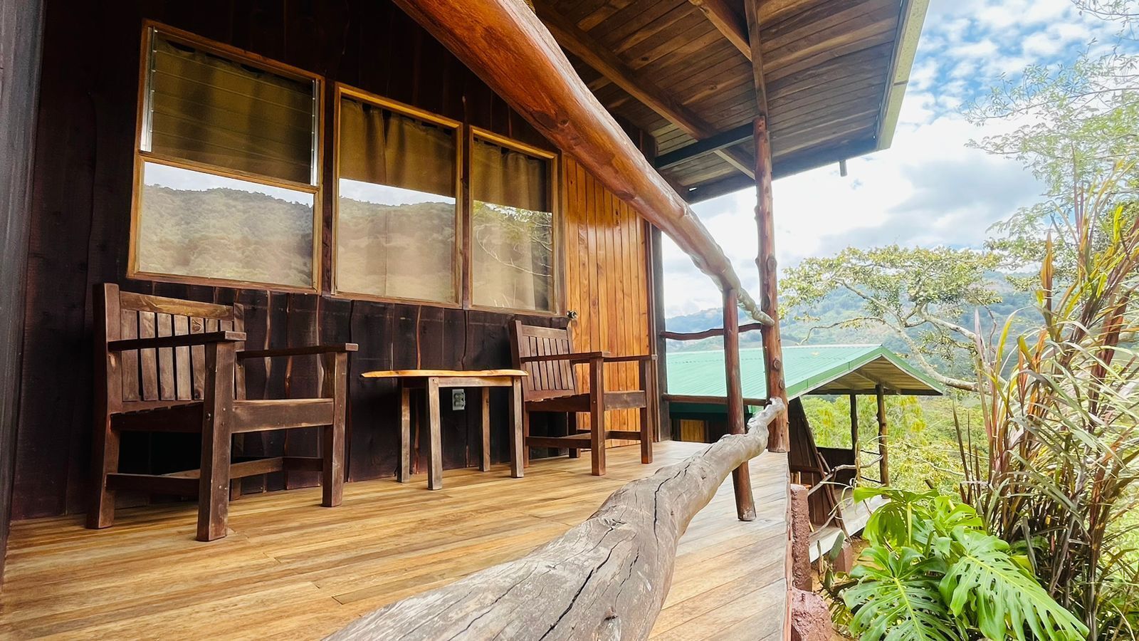 A wooden cabin with a porch, large windows, and a view of the mountains.