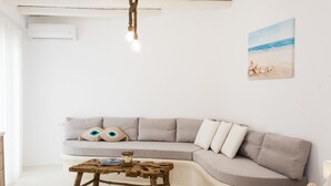 Un salon moderne avec un canapé gris aux lignes courbes, une table basse en bois et un tableau sur le thème de la plage accroché au mur.