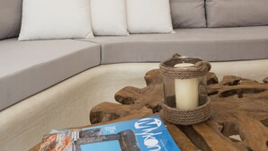 Un salon avec un canapé gris, une table basse en bois sur laquelle est posée une bougie, et un magazine.
