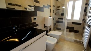 A modern bathroom with a black sink, white toilet, and a glass shower enclosure.