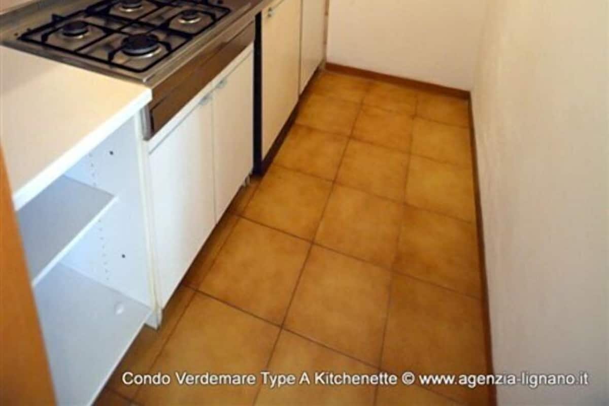 A compact kitchen with a gas stove, white cabinets, and a tiled backsplash.