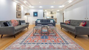 A modern living room with two grey sofas, a patterned rug, and a coffee table with magazines. - Mayfair Piccadilly Apartment (London)