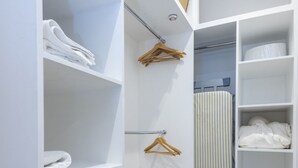 A walk-in closet with multiple shelves, a hanging rod, and an ironing board. - Mayfair Piccadilly Apartment (London)