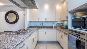 A modern kitchen with white cabinets, a granite countertop, a built-in microwave, and a gas stove. - Mayfair Piccadilly Apartment (London)
