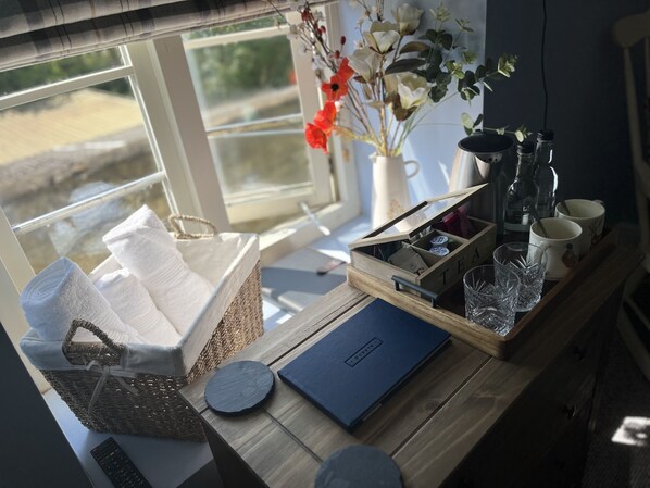 A wooden table with a basket of white towels, a wooden box labeled "TEA", and a blue folder. - The Crewe Arms (Brackley)
