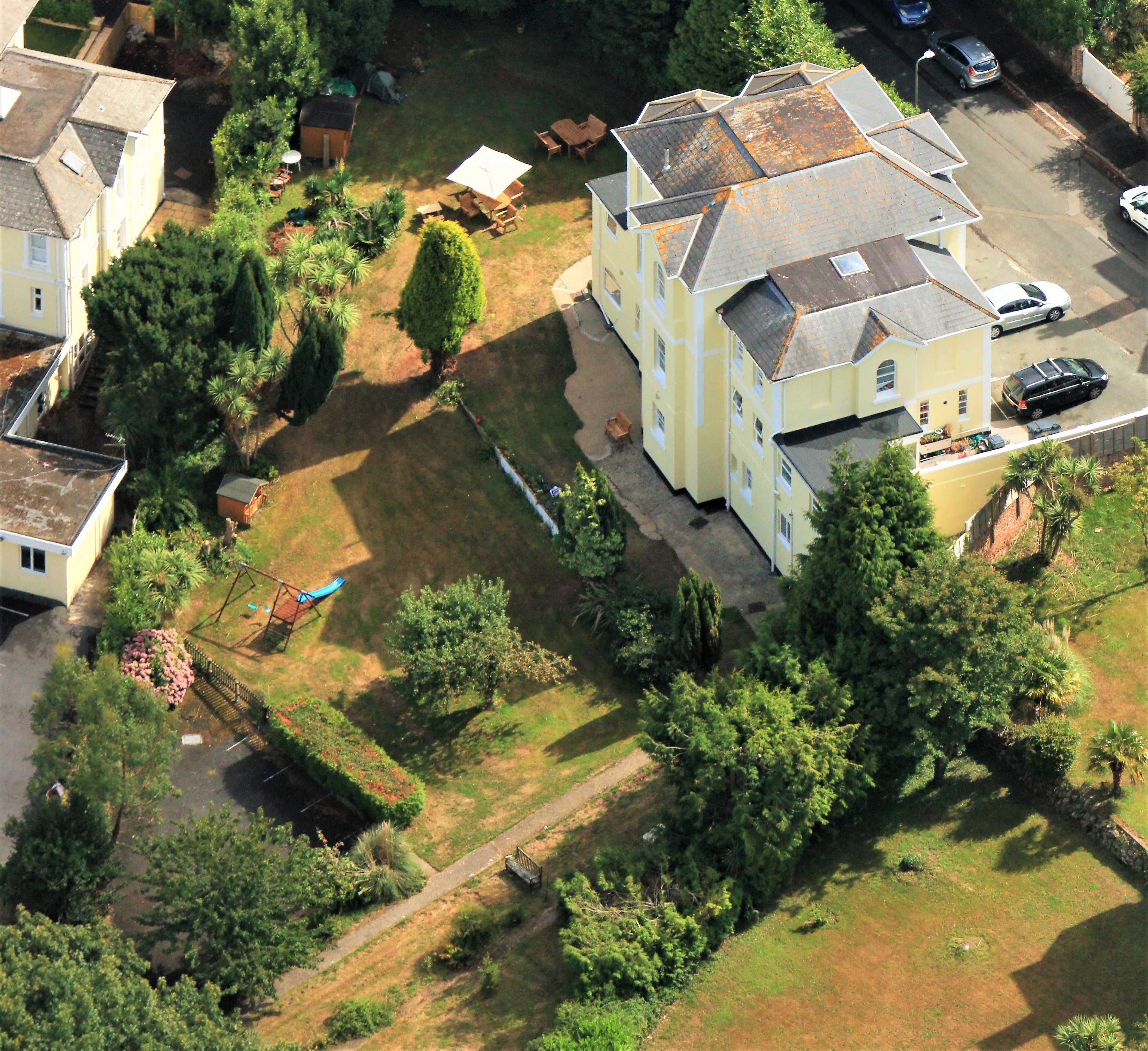 Vue aérienne d’un quartier résidentiel avec des maisons, une aire de jeux et un ciel dégagé.