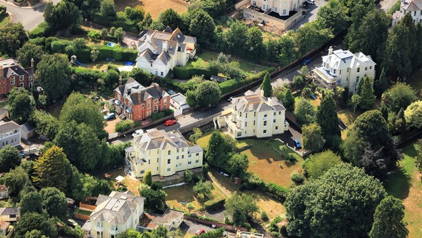Ovenudblik over et boligområde med huse, en jernbane og en lille park.