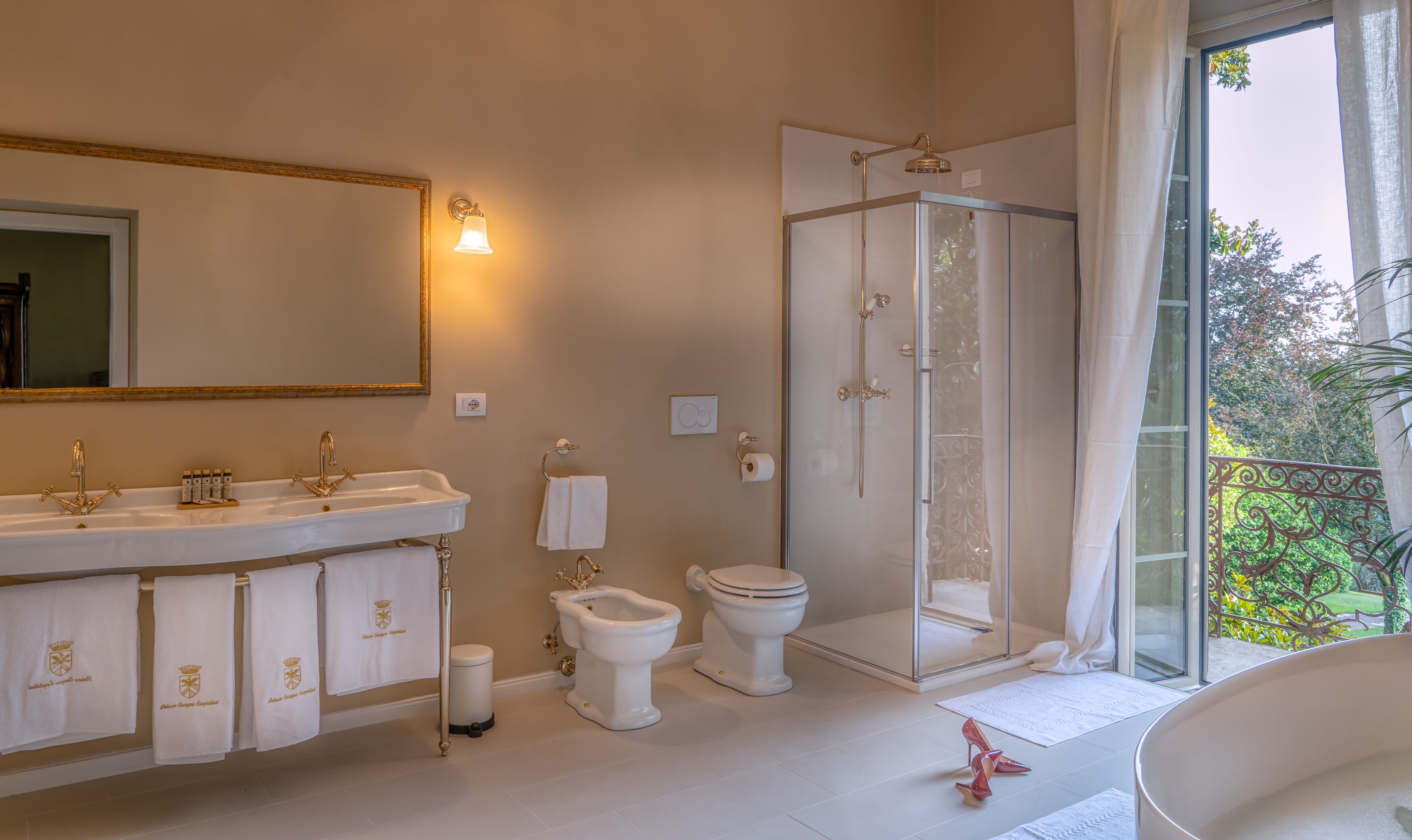 Een badkamer met een grote spiegel, twee wastafels, een toilet en een douchecabine.