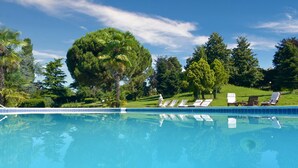 Una piscina con agua azul cristalina, rodeada de exuberante vegetación y árboles.