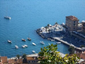A coastal marina with boats docked, a promenade, and buildings with balconies. - Vittoria Porto Santo Stefano (Monte Argentario)