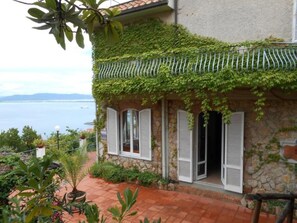 A stone house with a balcony, white shutters, and a view of the sea. - Vittoria Porto Santo Stefano (Monte Argentario)