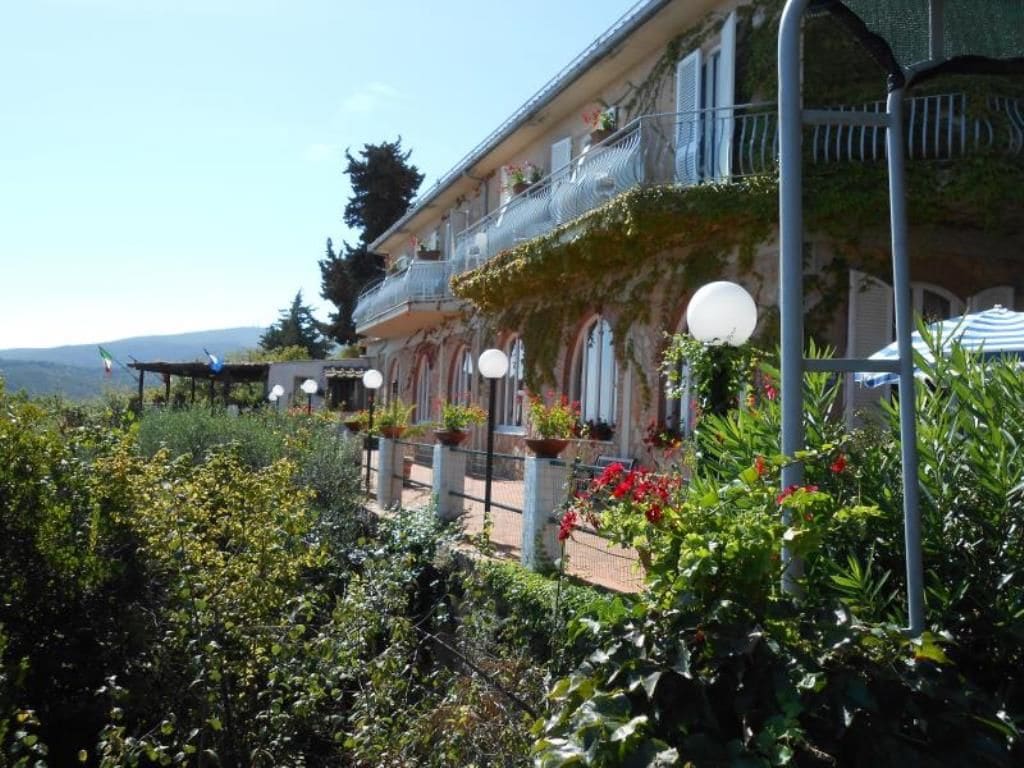 A building with a balcony, potted plants, and a view of the landscape.