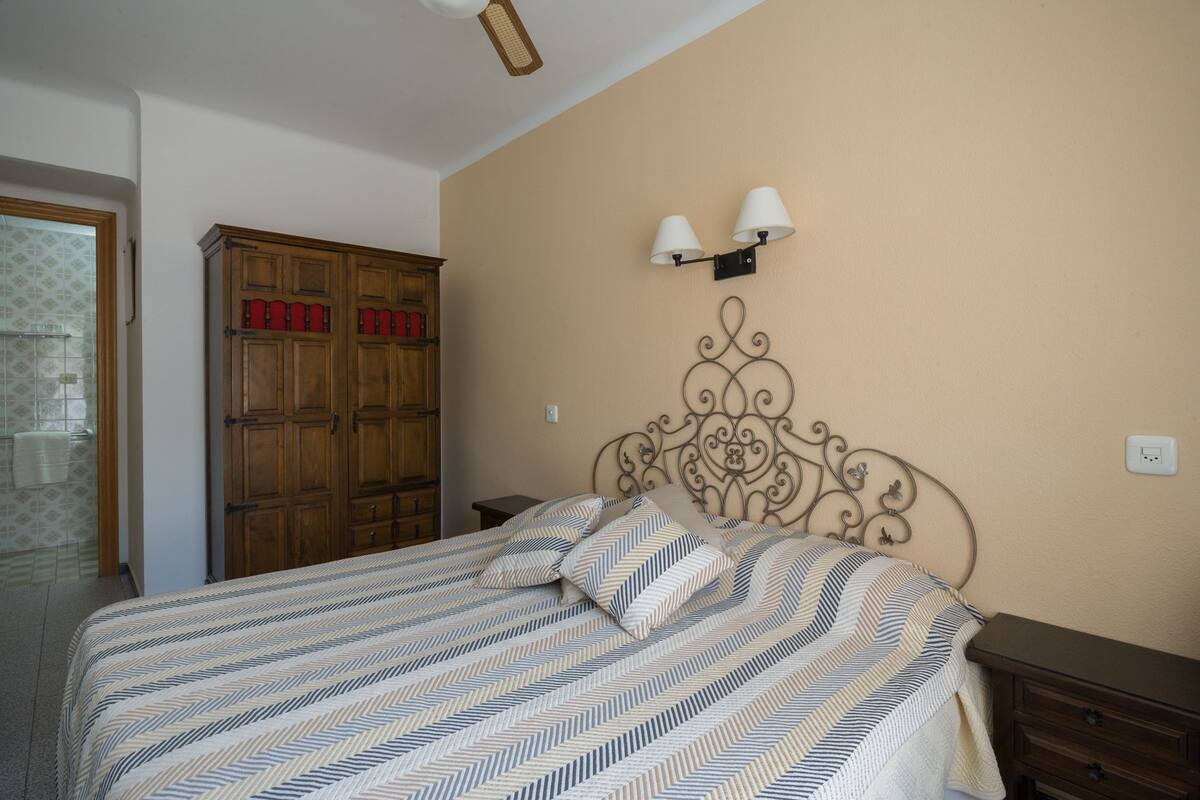 A bedroom with a bed, a wardrobe, and a wall-mounted light fixture.