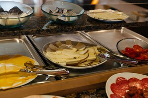 En buffet med forskellige retter, herunder ost, tomater og andet mad.