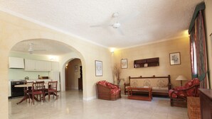 A spacious living area with a dining table, chairs, sofas, and a kitchen in the background. - Satori Gozo Centre (Xaghra)