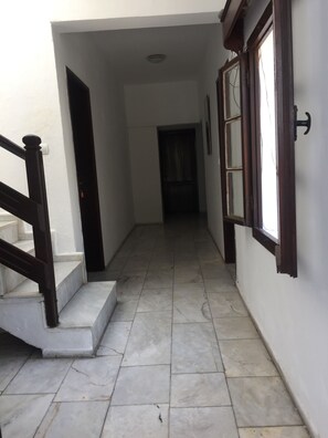 A hallway with a staircase leading to an upper floor, tiled flooring, and a door at the end. - NEW SEDAN PANSIYON (Bodrum)