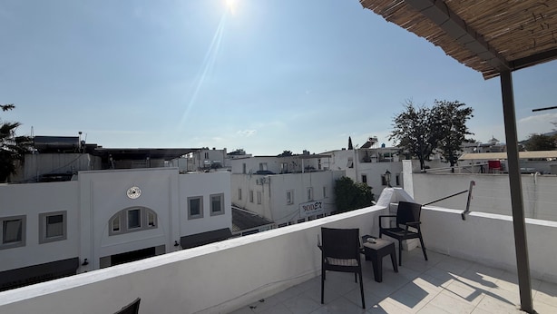 A rooftop terrace with a view of surrounding buildings, a pergola, and a few chairs. - NEW SEDAN PANSIYON (Bodrum)