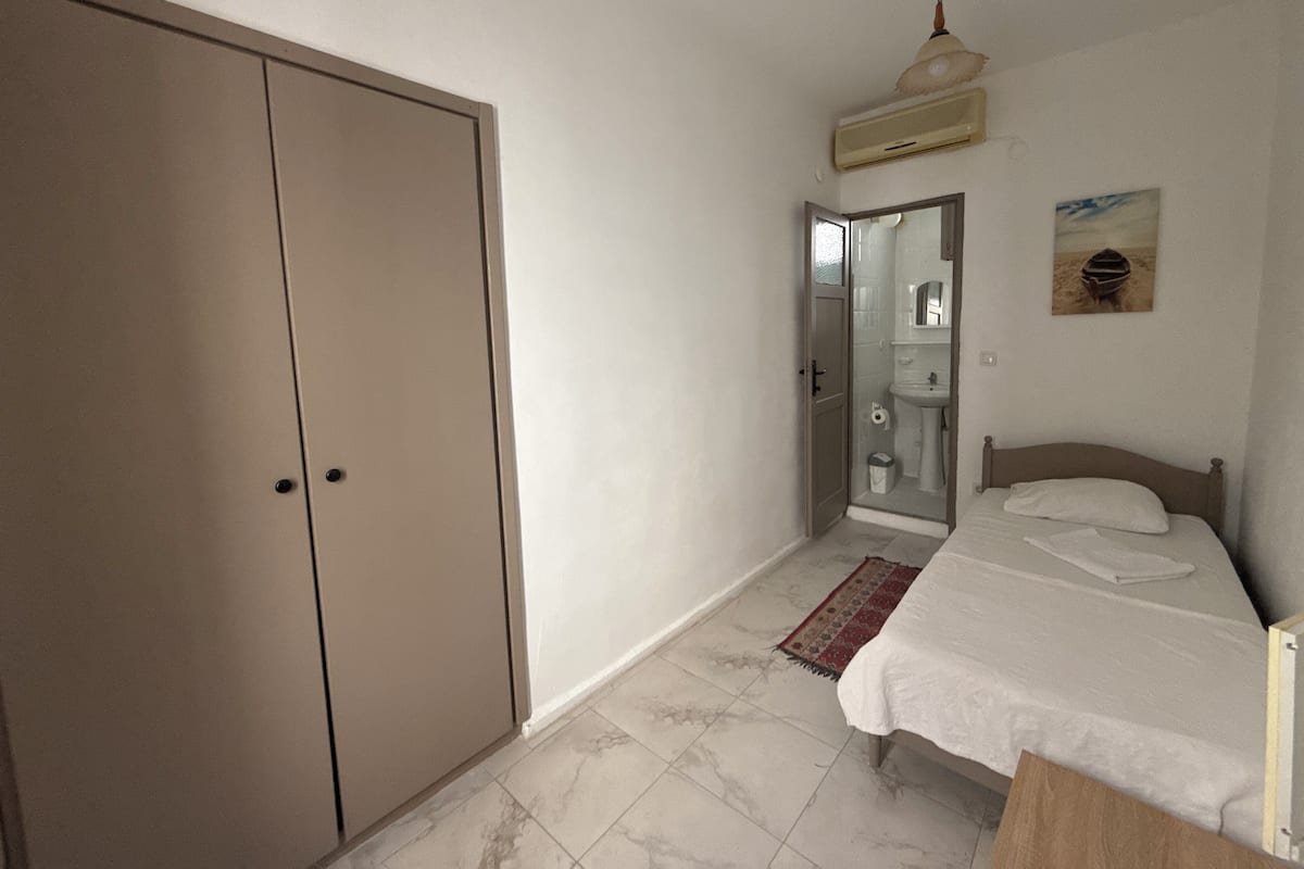 A bedroom with a bed, a wardrobe, a bathroom, and a ceiling fan.