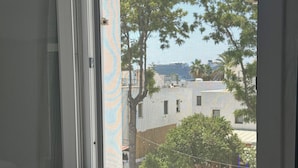 A room with a window overlooking a residential area, a bed, and a small table. - NEW SEDAN PANSIYON (Bodrum)
