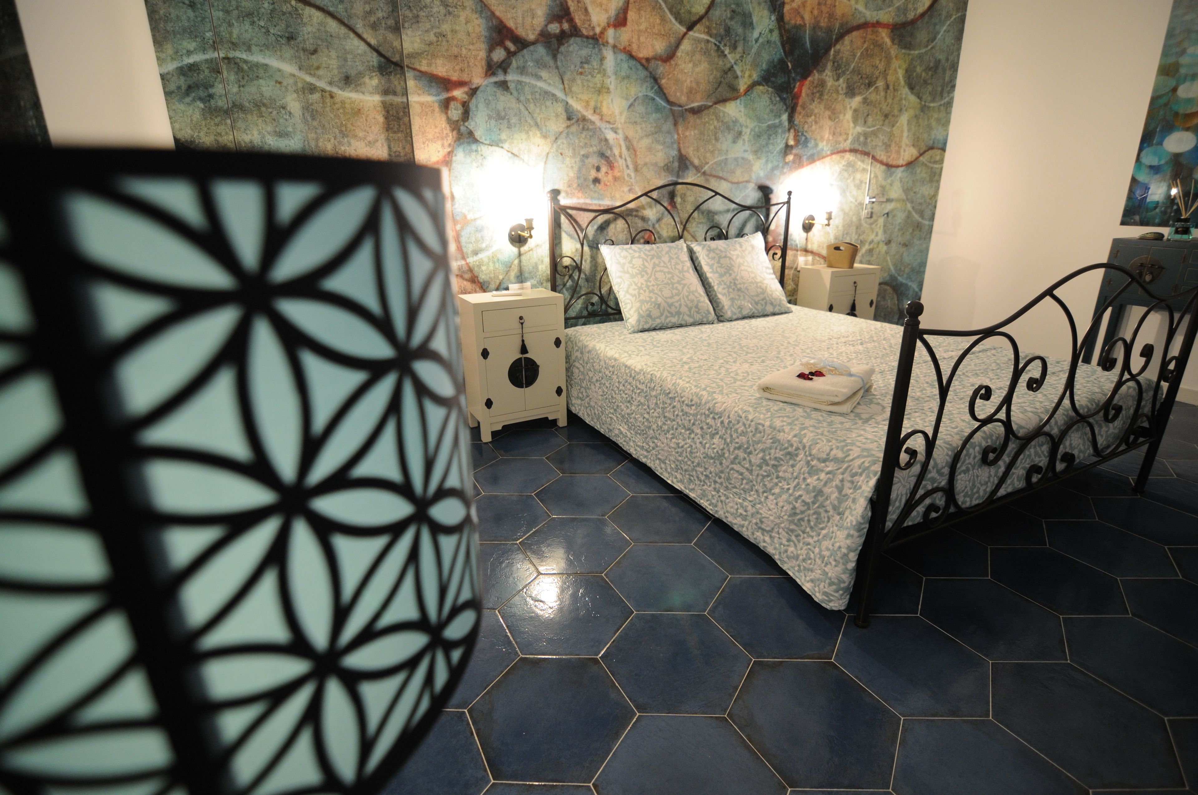 A bedroom with a bed, nightstands, and a decorative wall.