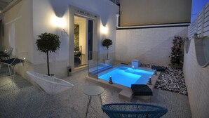 A modern outdoor pool area with a glass enclosure, seating, and a small table. - QuattroCuori Boutique Hotel & Spa (Portopalo di Capo Passero)