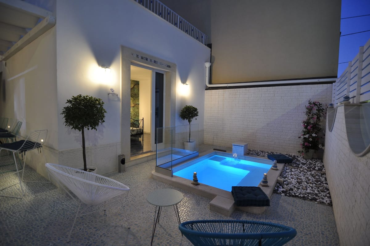 Uma área de piscina moderna ao ar livre, com cobertura de vidro, assentos e uma pequena mesa.