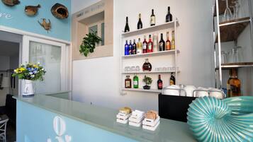 A reception area with a glass counter, shelves with bottles and glasses, a potted plant, and a decorative vase.