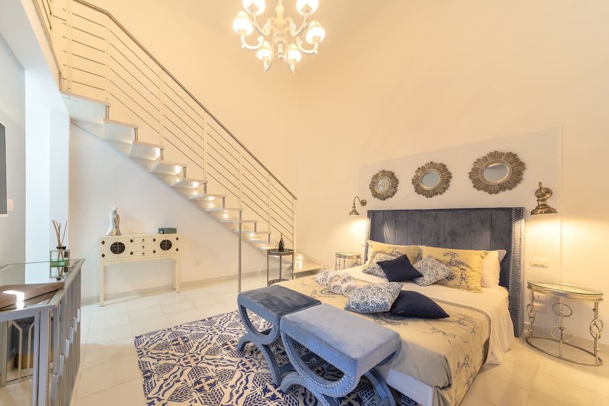 Um quarto moderno com escada, cama com roupa de cama estampada e um lustre.