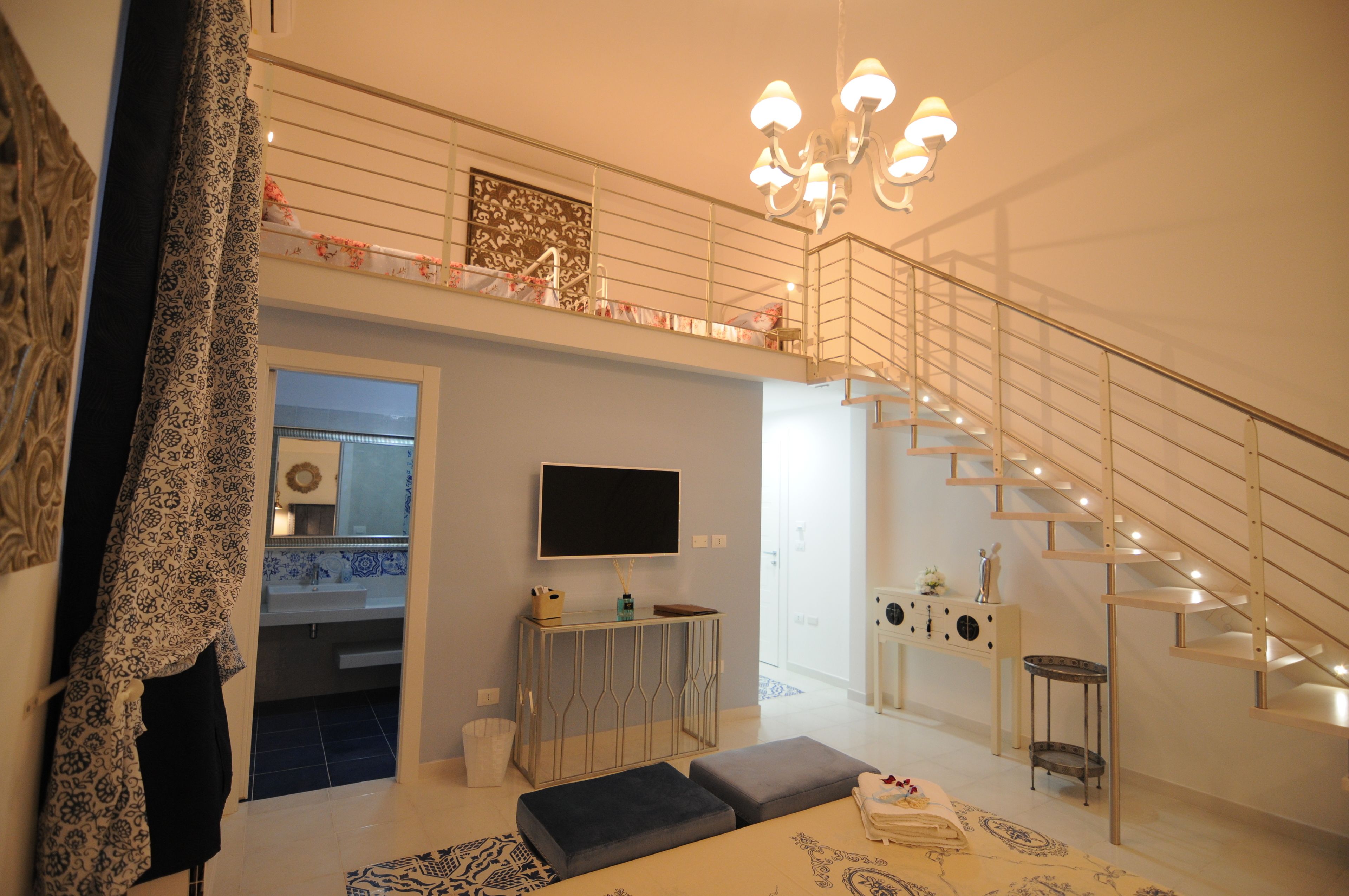 A modern living room with a staircase, a flat-screen TV, and a console table.