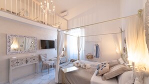 A bedroom with a four-poster bed, a vanity with a mirror, a television, and a balcony with a railing. - QuattroCuori Boutique Hotel & Spa (Portopalo di Capo Passero)