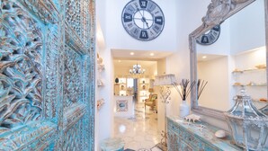 A hallway with a decorative blue door, a large wall clock, a mirror, and a patterned floor. - QuattroCuori Boutique Hotel & Spa (Portopalo di Capo Passero)