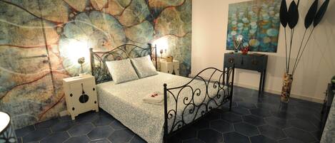 A bedroom with a bed, nightstands, a wall art piece, and a decorative vase.