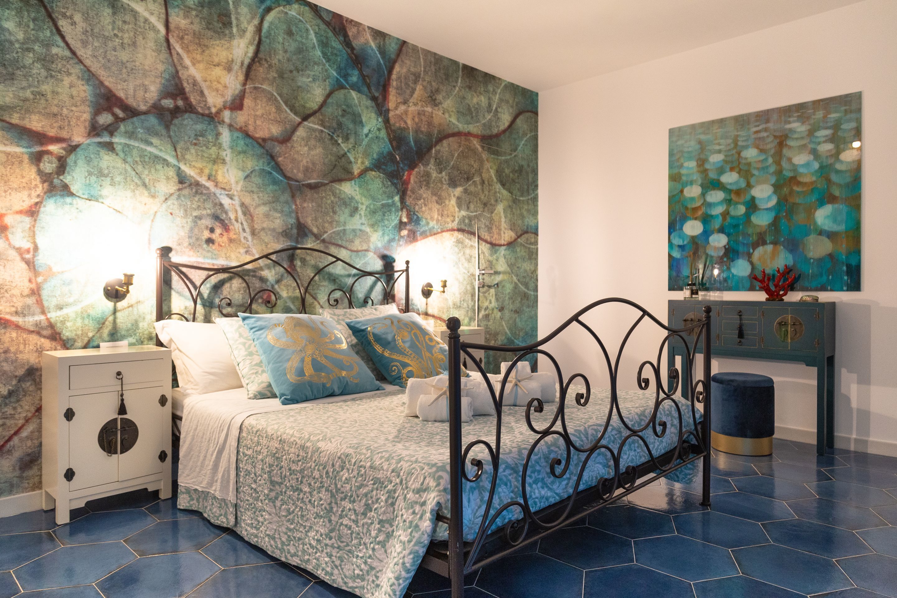 A bedroom with a bed, nightstands, a dresser, and a large abstract painting on the wall.