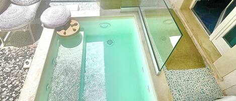 An indoor swimming pool with lounge chairs and a sunbed.