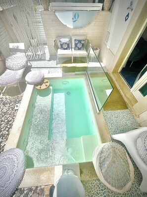 An indoor swimming pool with lounge chairs and a sunbed.