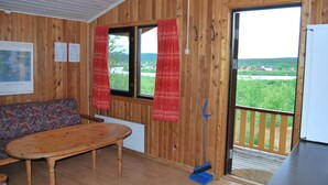 Un intérieur en bois avec un canapé, une table et une vue sur la verdure à l’extérieur.