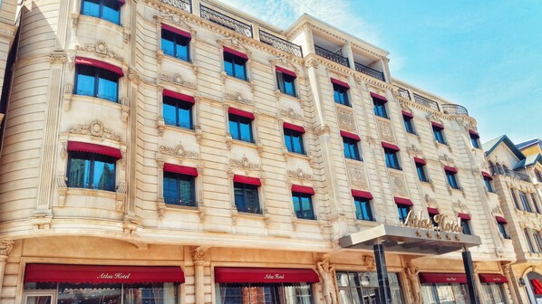 Ett hotell med flera våningar, röda markiser, utsmyckade arkitektoniska detaljer och balkonger.