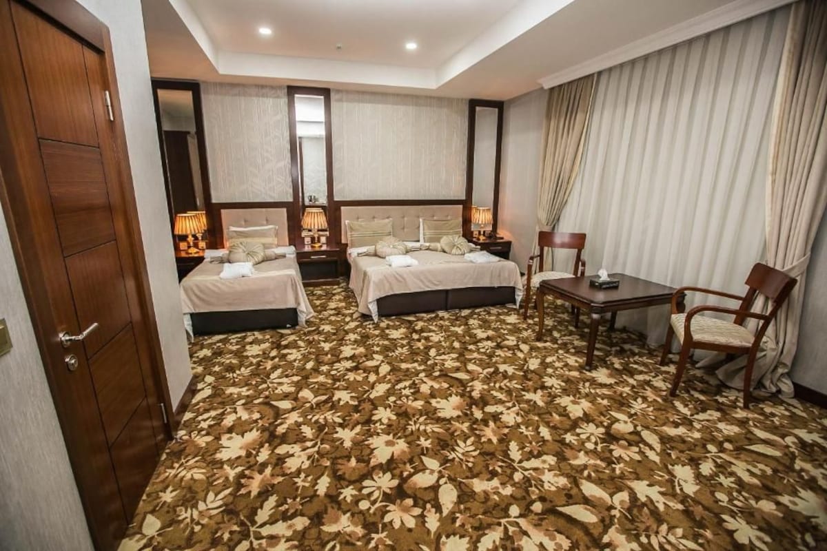 A hotel room with two beds, a desk, and a chair.