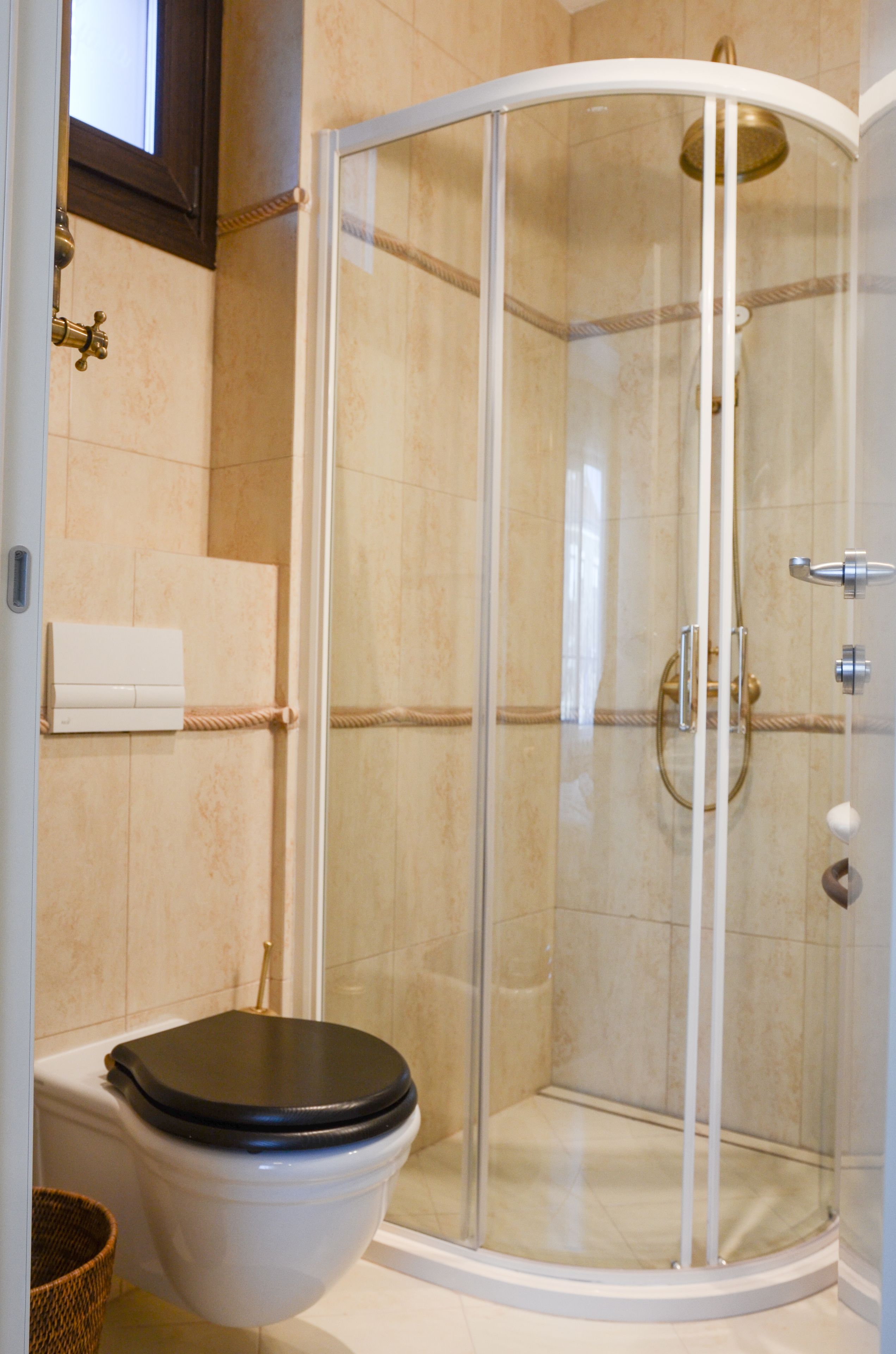 A bathroom with a glass-enclosed shower, a toilet, and a towel rack.
