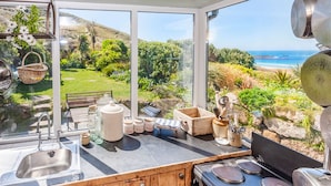 A kitchen with a view of a beach and garden. - Petra, Beach Cottage, Great Sea Views, Garden (Sennen)