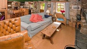 Ein rustikales Wohnzimmer mit Ledersofa, Couchtisch aus Holz und Kamin aus Stein.