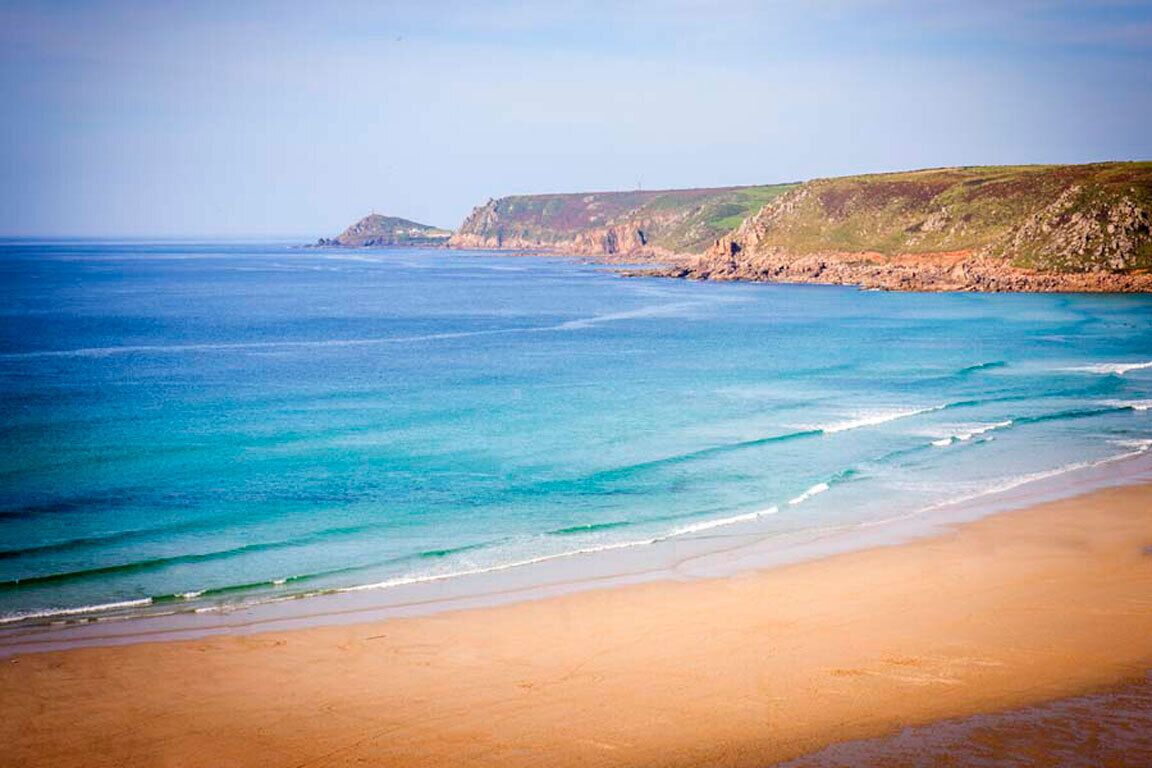 A beach with clear blue water and a sandy shore.