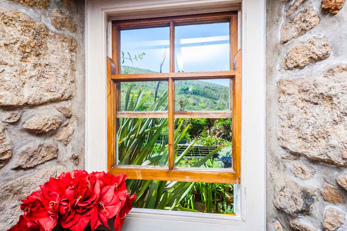 A window with a stone wall and a view of greenery.