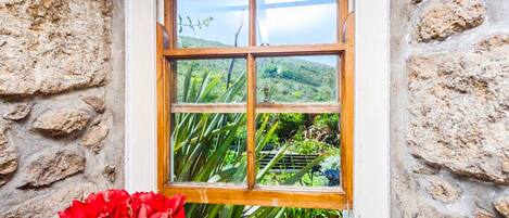 A window with a stone wall and a view of greenery.