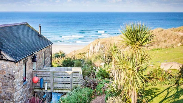A stone building with a wooden deck overlooking a beach and ocean. - Girl Annie, Beach Cottage, Great Sea-Views, Garden (Sennen)