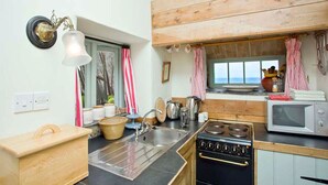 Una cocina con estufa, pileta y alacenas de madera.