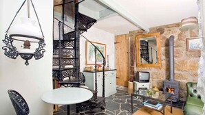 Una sala de estar acogedora con suelo de piedra, chimenea, televisor y un sofá de cuero verde.