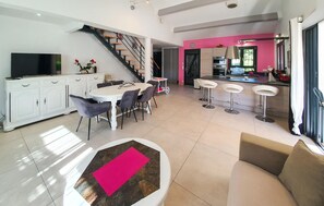 A modern kitchen with a dining area, a staircase, and a bar.